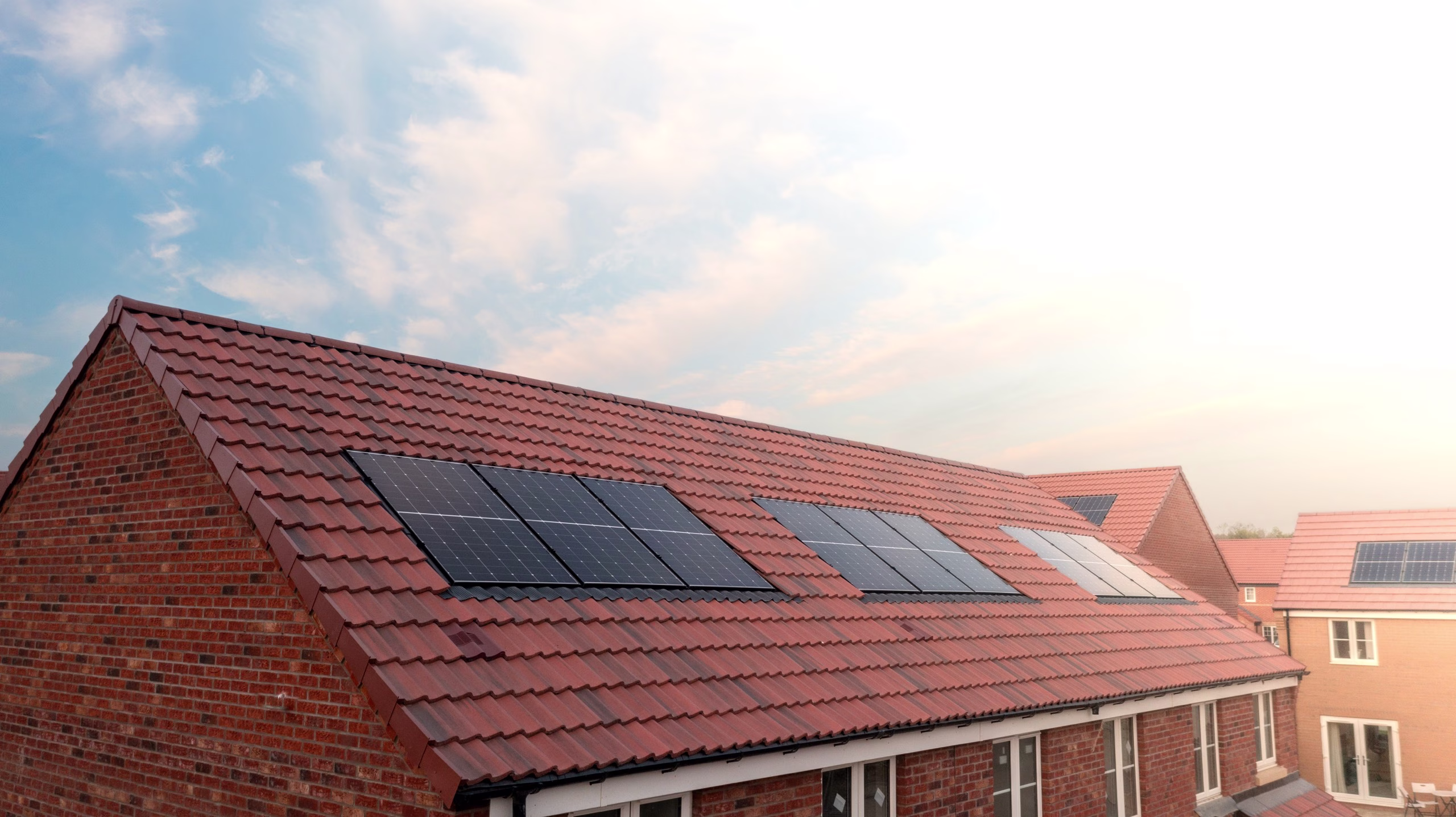 The roof of a row of new build houses on a construction site with roof integrated or In-Roof solar panels for cheap and sustainable energy in an eco friendly property